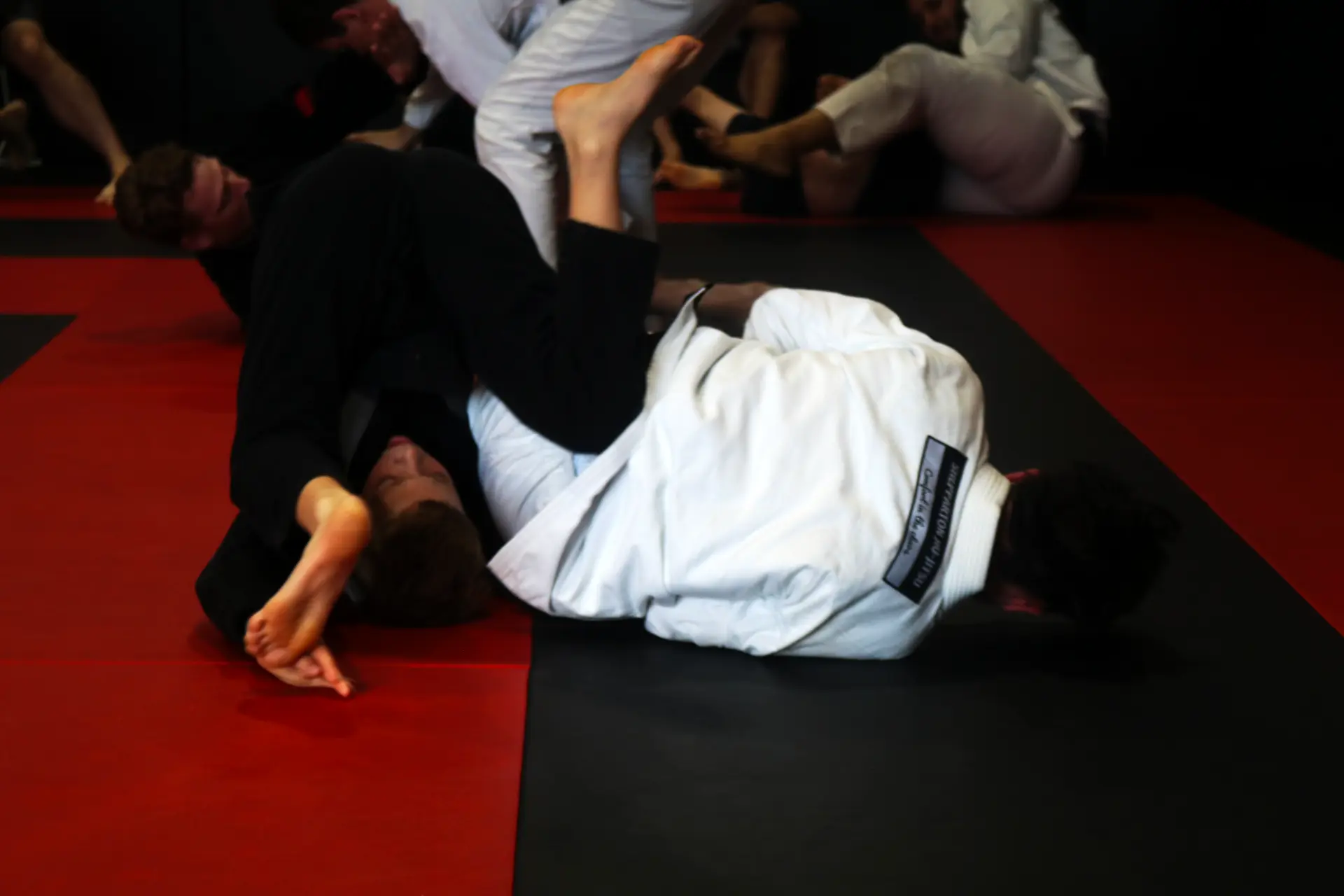 Members rolling in gis on the red and black mats